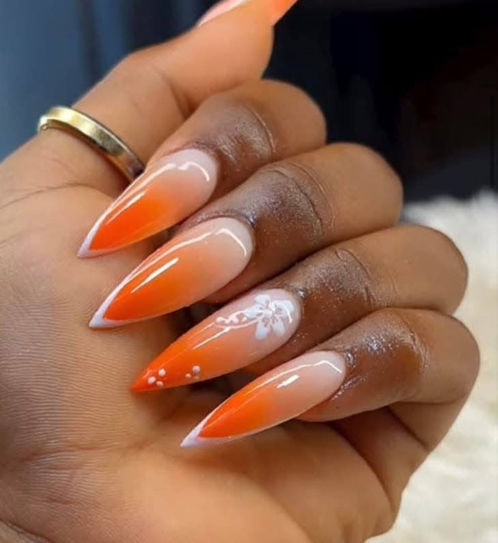 Pose stiletto ombré orange avec nail art fleuri, réalisée chez Nova House