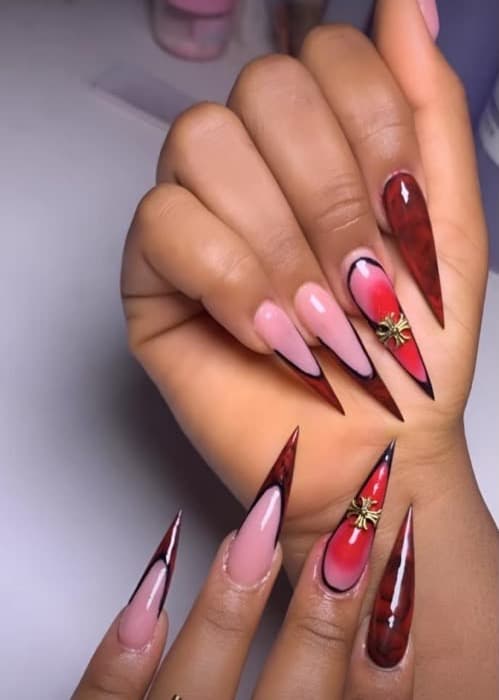 Pose stiletto rouge et noire avec bijoux d'ongles, réalisée chez Nova House