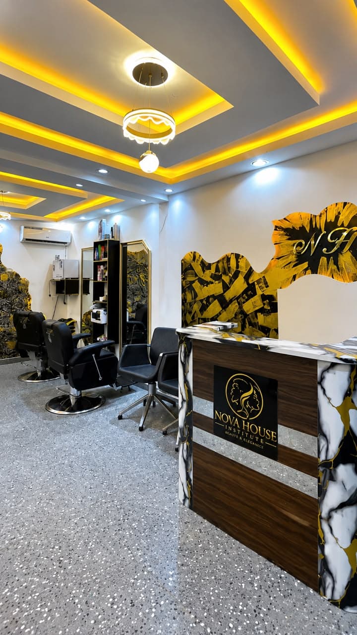 L'accueil de Nova House : comptoir marbré noir et or au logo de l'institut, face aux fauteuils de coiffure